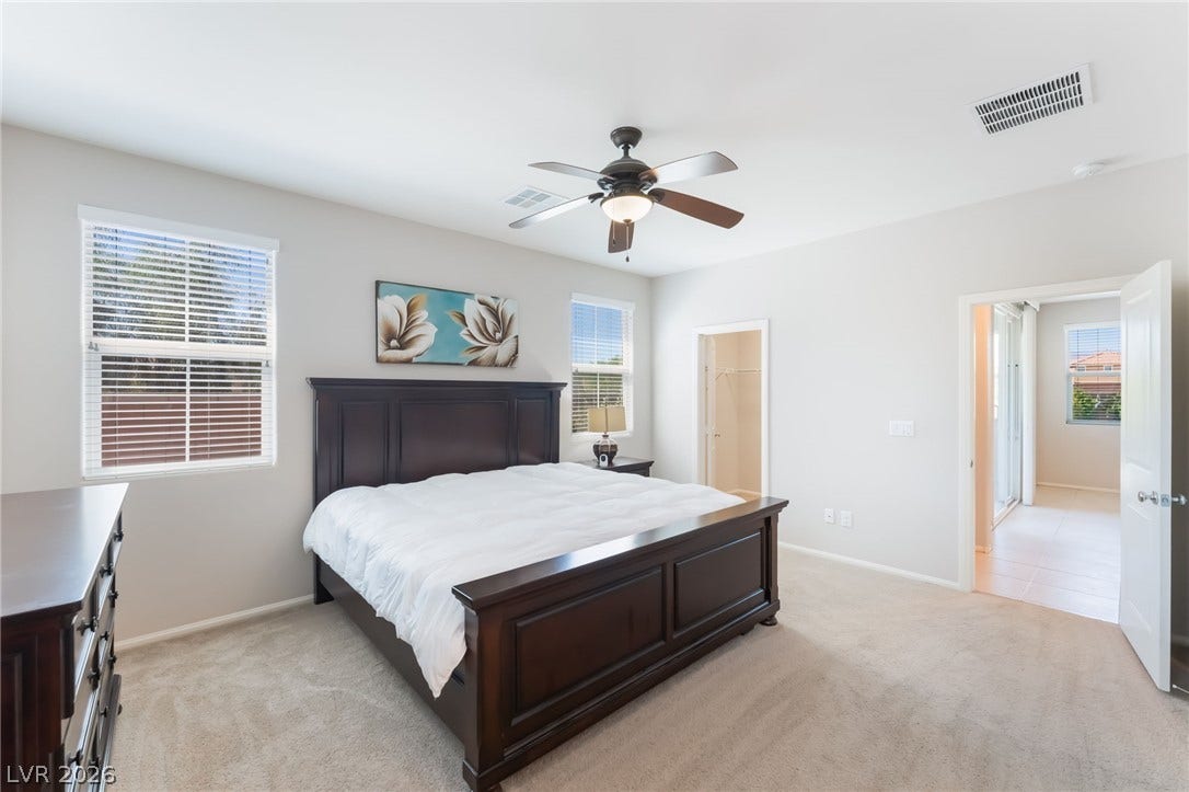 Soft carpeting underfoot and multiple windows define this comfortable primary bedroom suite.