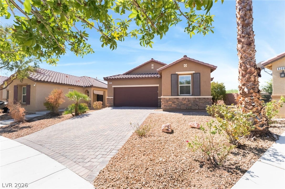 An inviting stone-accented facade fronts this single-story residence complete with a paved driveway.