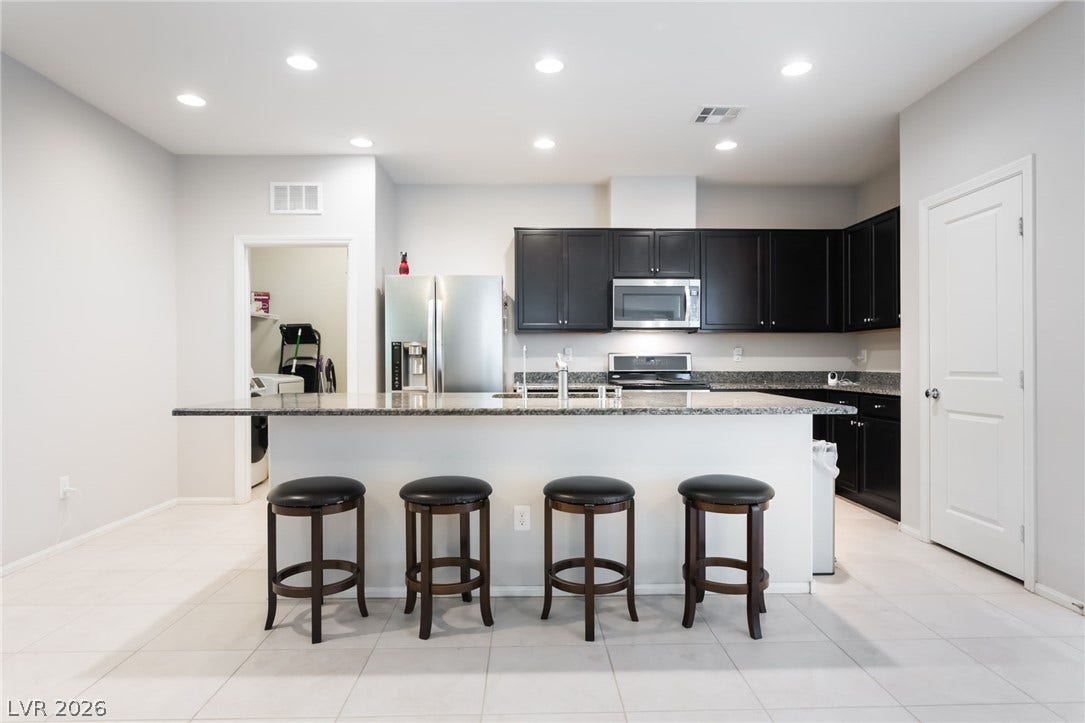 A spacious kitchen features granite countertops, sleek cabinetry, and tiled flooring.