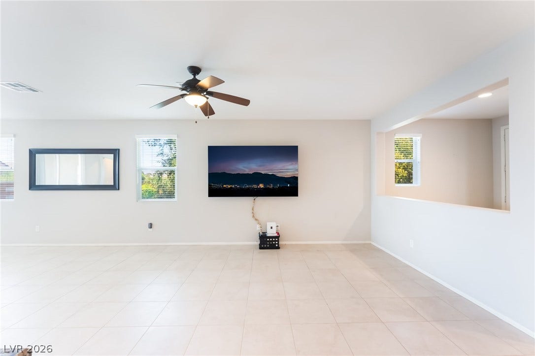 An open living space features clean tile flooring and a large wall cutout.