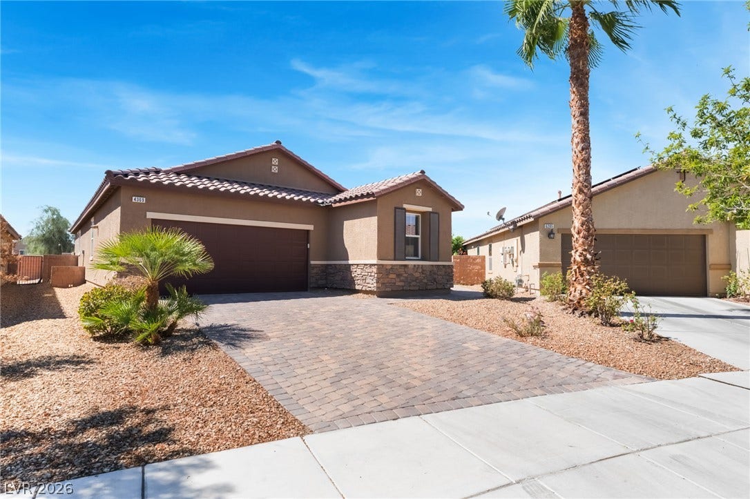 Desert landscaping and a paved driveway complement this single-story home with stone accents.