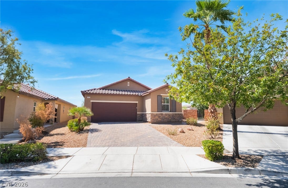 Spanish tile roofing and stone accents define this single-story home with a paved driveway.