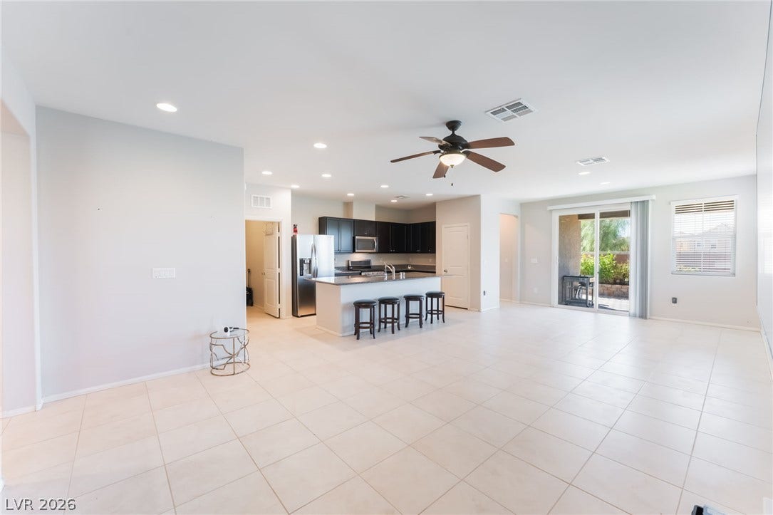 An open floor plan connects the tiled living space with a modern kitchen.