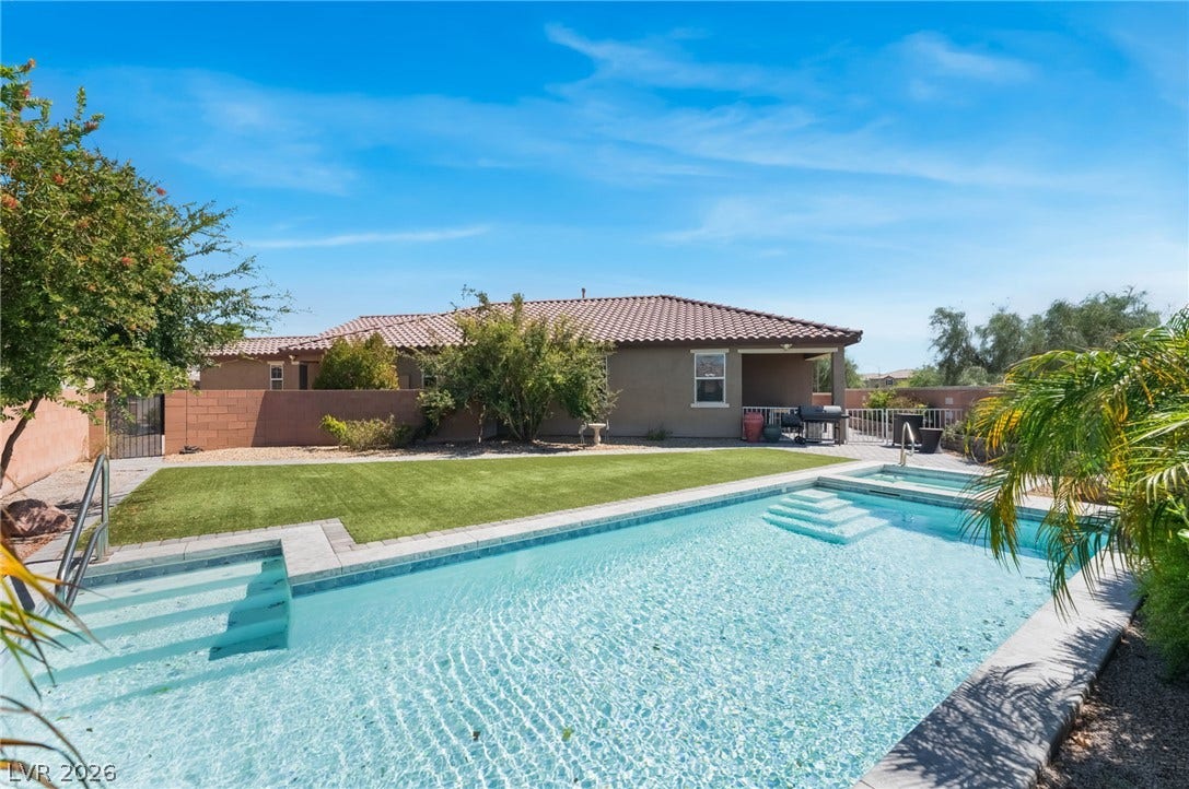 A sparkling swimming pool anchors the backyard of this tile-roofed home under sunny skies.