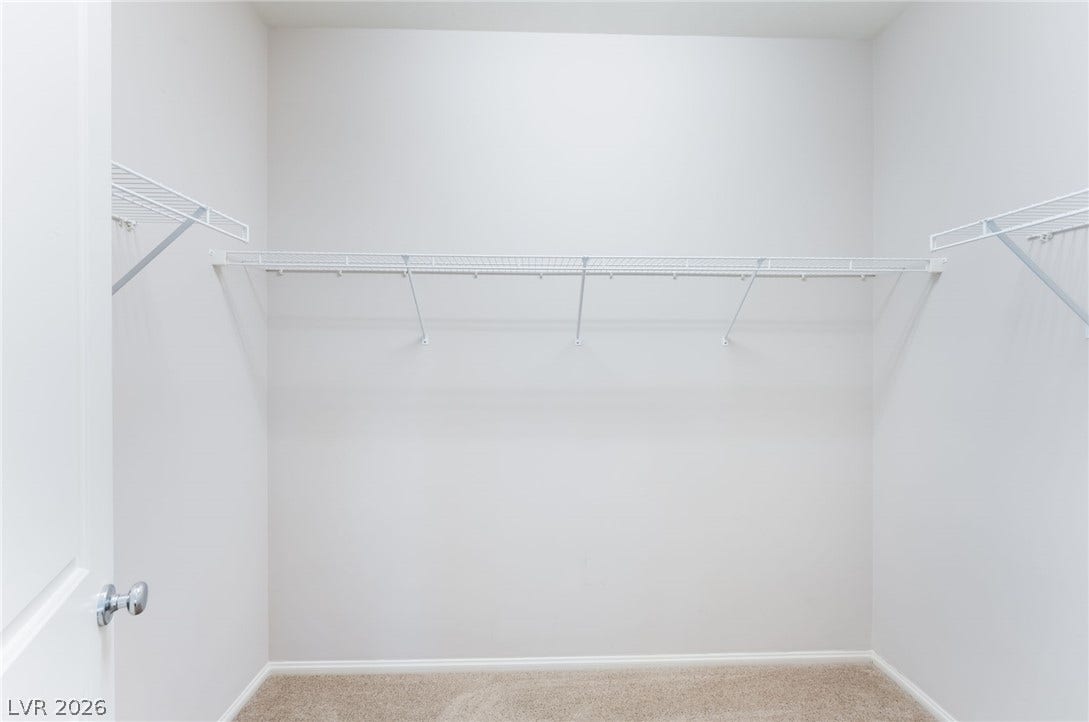 Ample wire shelving lines this functional walk-in closet space with neutral carpet.