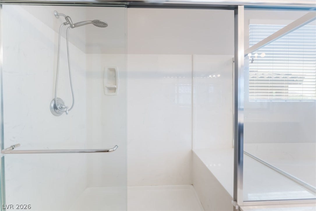 A sleek walk-in shower features glass doors and integrated seating.