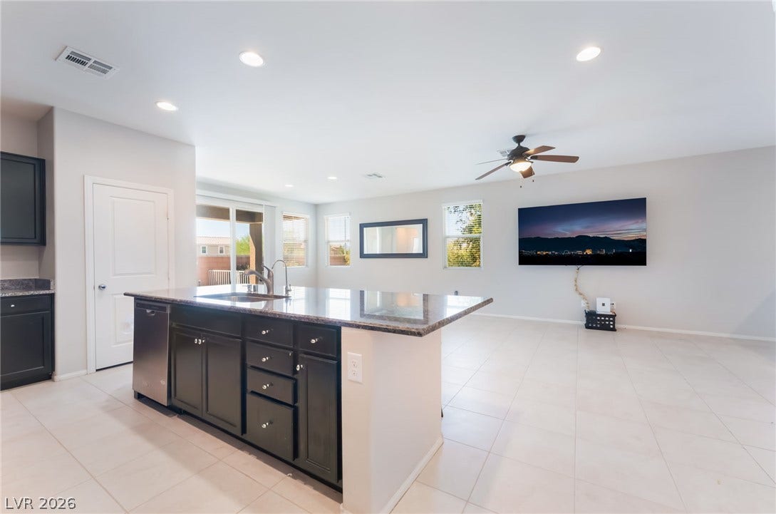 Granite countertops and dark cabinetry anchor a seamless connection to the adjacent living area.