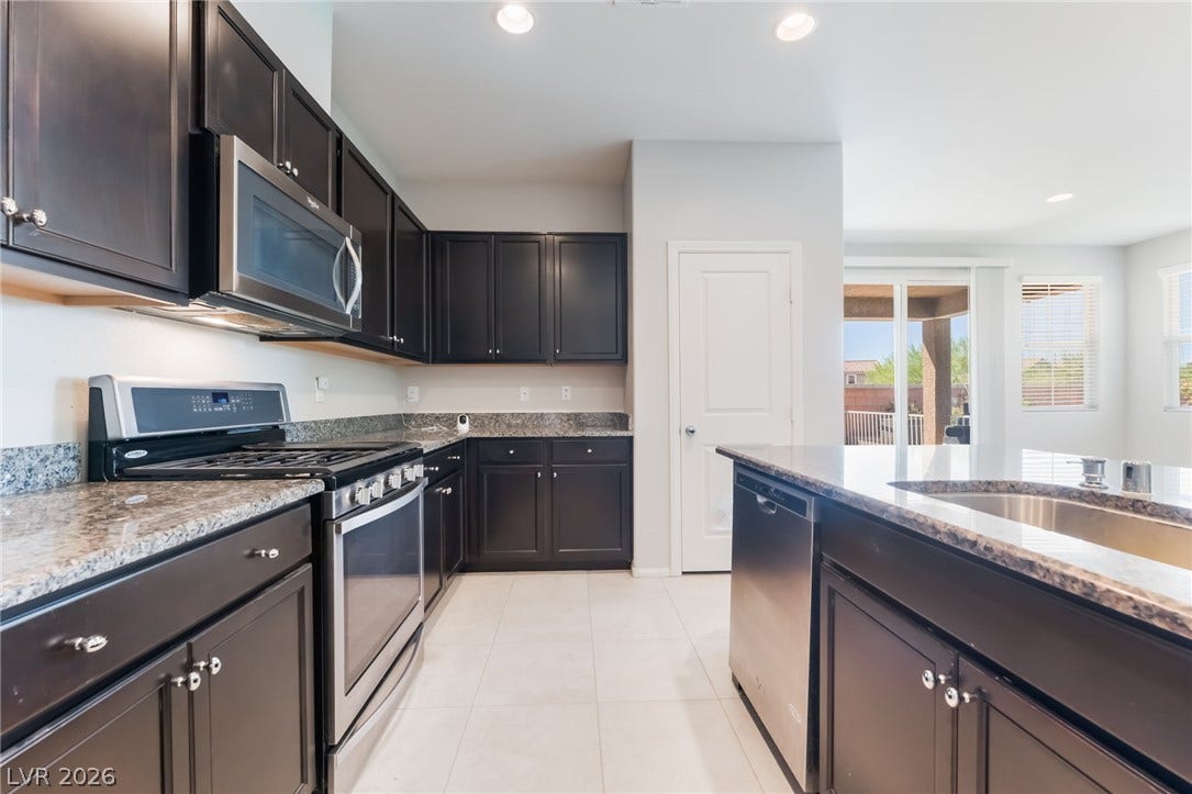 Dark cabinetry and granite countertops frame a modern culinary space.