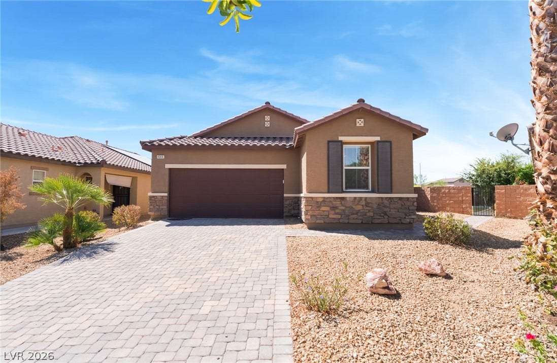An inviting stone-accented facade stands out against a paved driveway under clear blue skies.