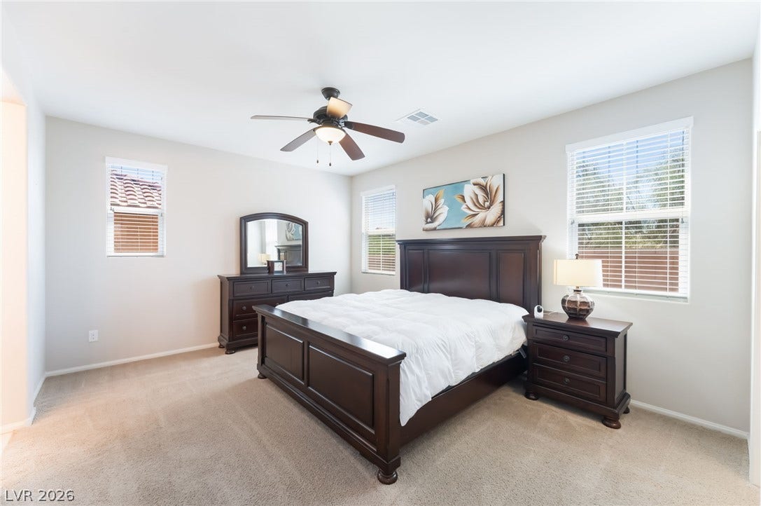 Plentiful natural light filters through multiple windows onto the soft carpeted flooring.