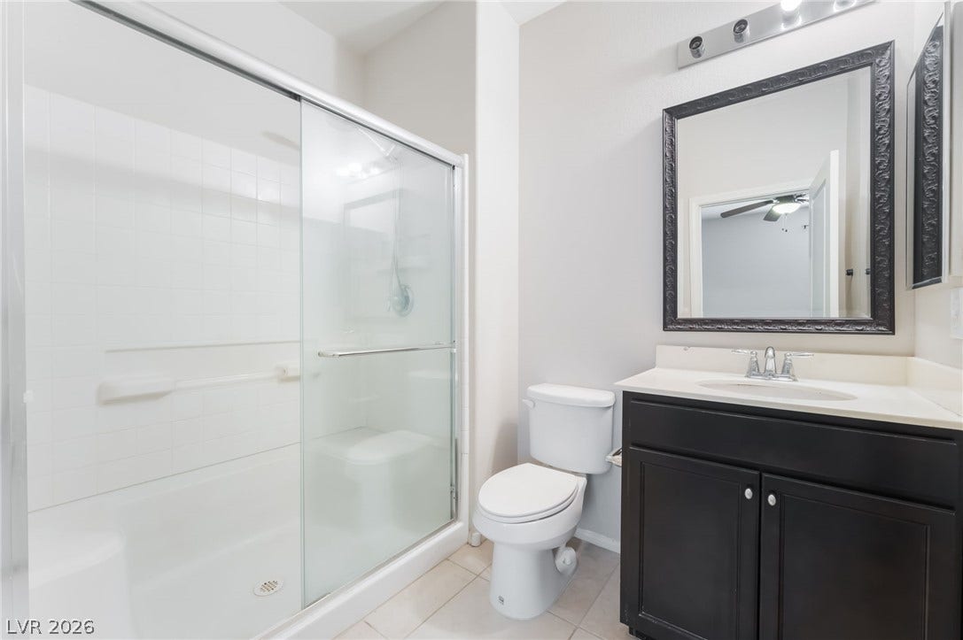 A classic dark wood vanity contrasts with light tile flooring in this clean bathroom.