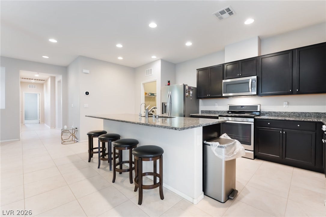 A spacious modern kitchen features solid countertops and an expansive central island.