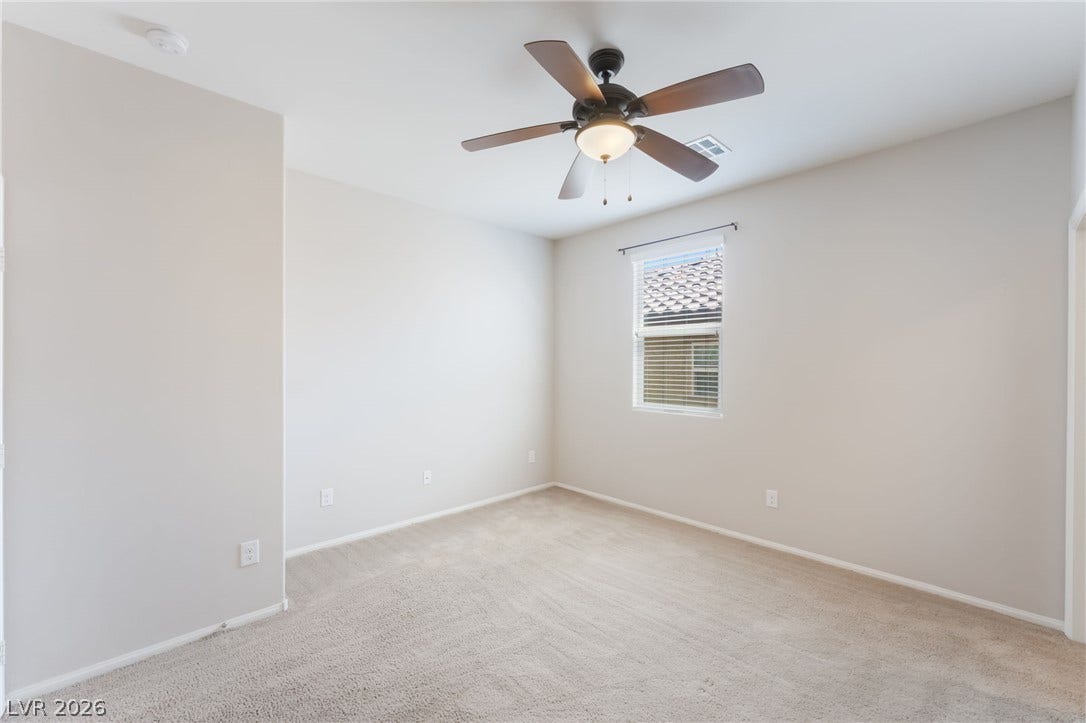 Plush carpeting and a classic multi-paned window define this serene bedroom space.