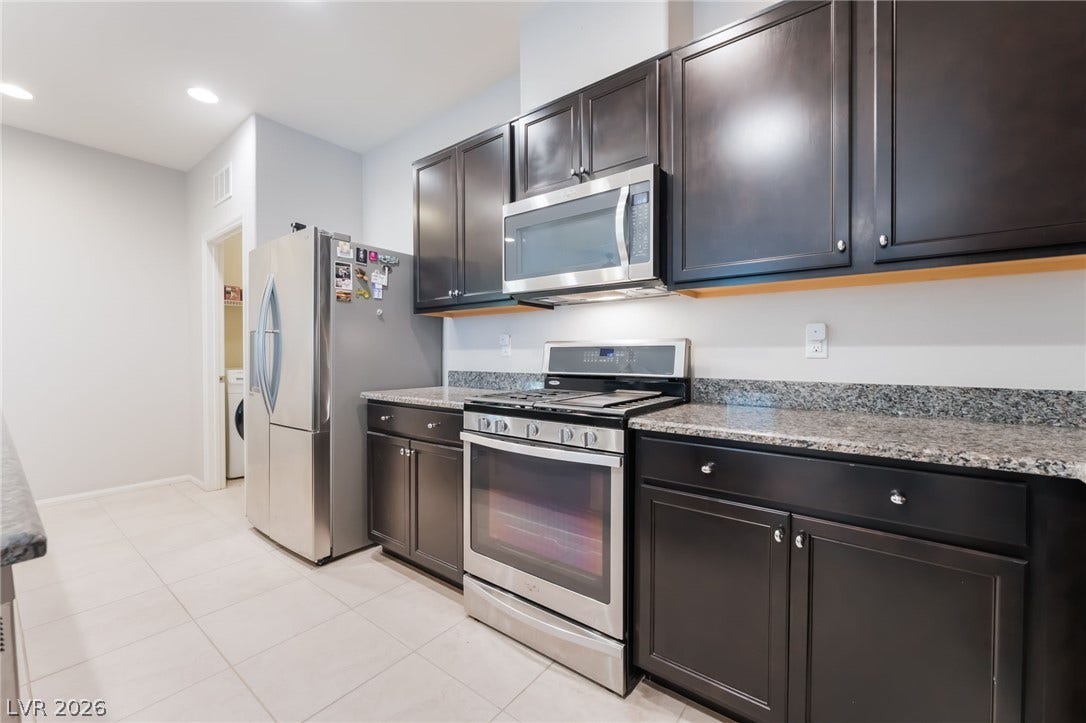 Gleaming granite countertops pair beautifully with rich dark cabinetry and stainless steel appliances.
