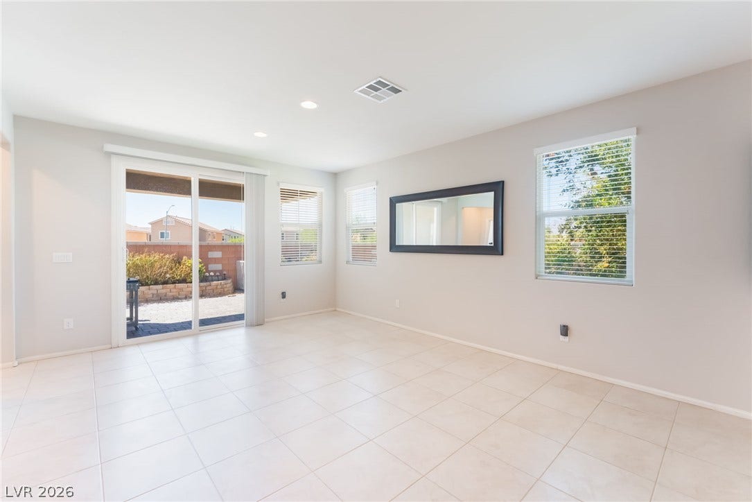 Sliding glass doors open directly to the backyard patio from this tile-floored living area.