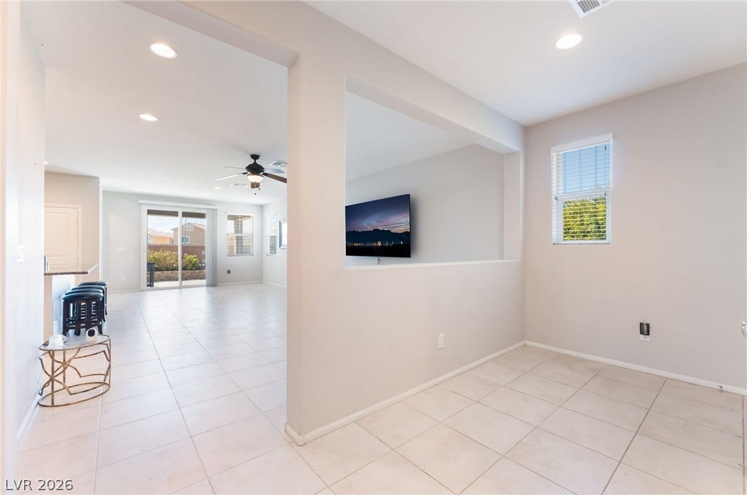 An open-concept layout connects flexible living spaces elevated by clean tiled flooring.