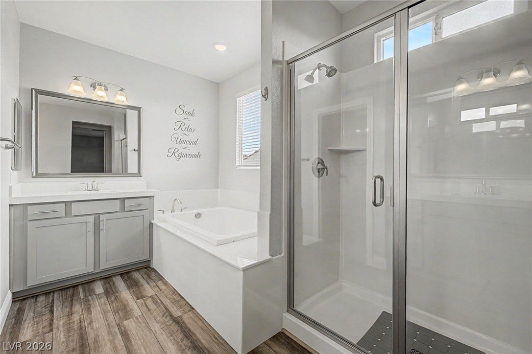 4618 Summer Azure Street, North Las Vegas, NV 89031 An inviting bathroom offers a deep soaking tub alongside a modern glass-enclosed shower.