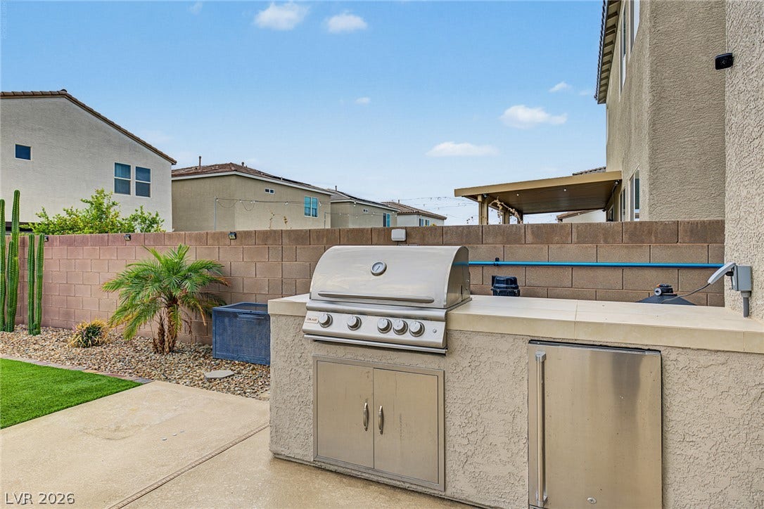 4618 Summer Azure Street, North Las Vegas, NV 89031 An integrated outdoor kitchen features a built-in stainless steel grill set against a block wall.
