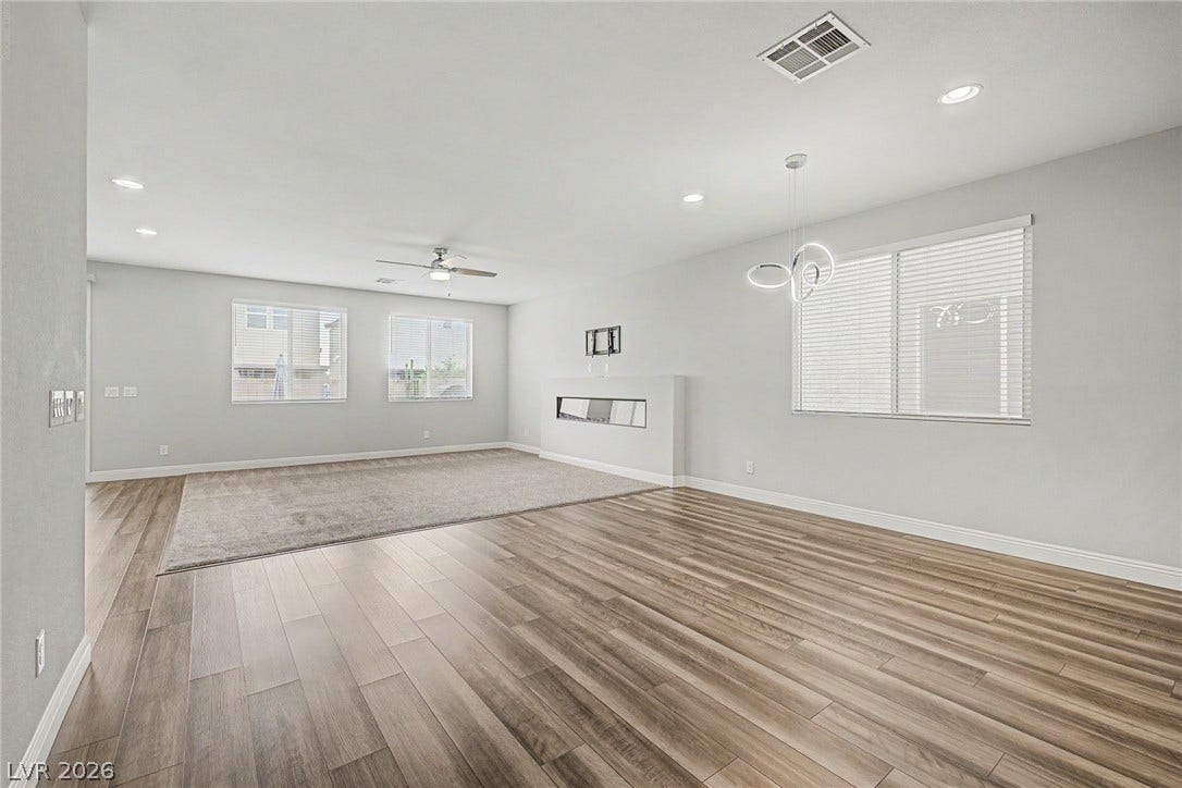 4618 Summer Azure Street, North Las Vegas, NV 89031 Gleaming wood-look floors, tall windows, and a modern linear fireplace define this open interior.
