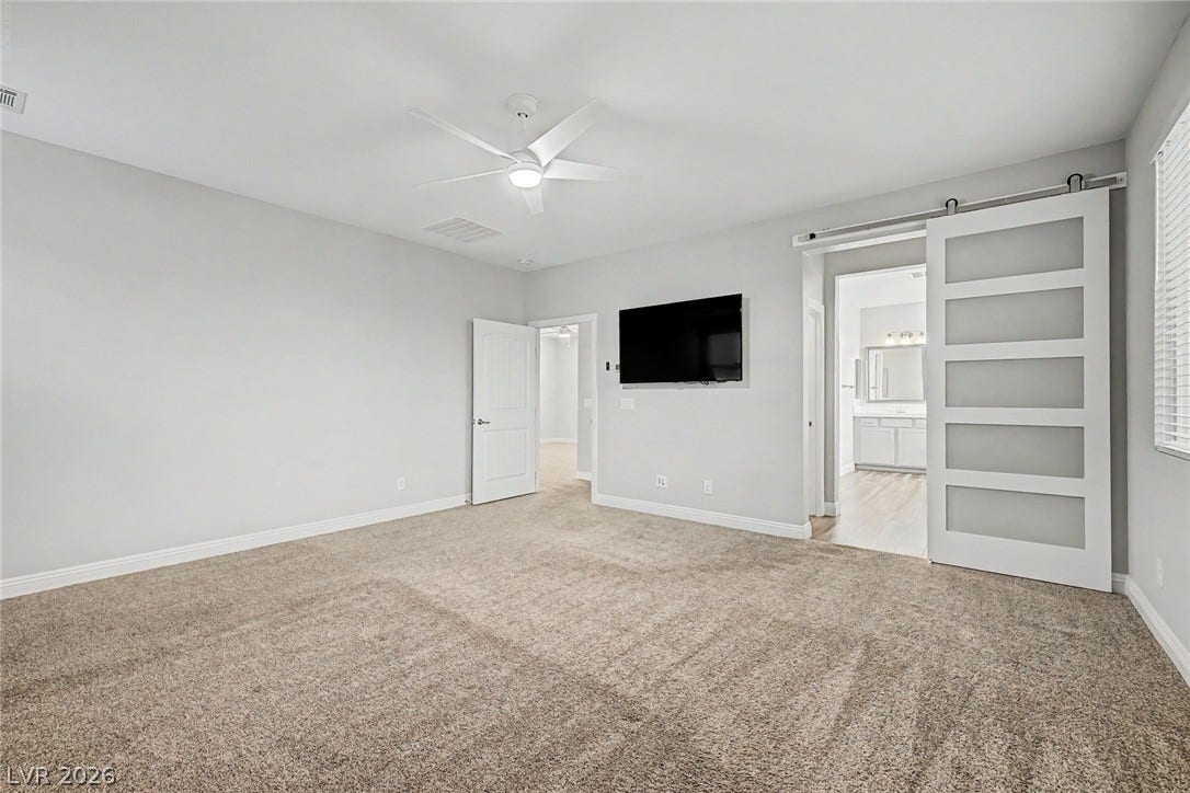 4618 Summer Azure Street, North Las Vegas, NV 89031 Plush carpeting anchors this spacious bedroom featuring a modern sliding barn door entry.