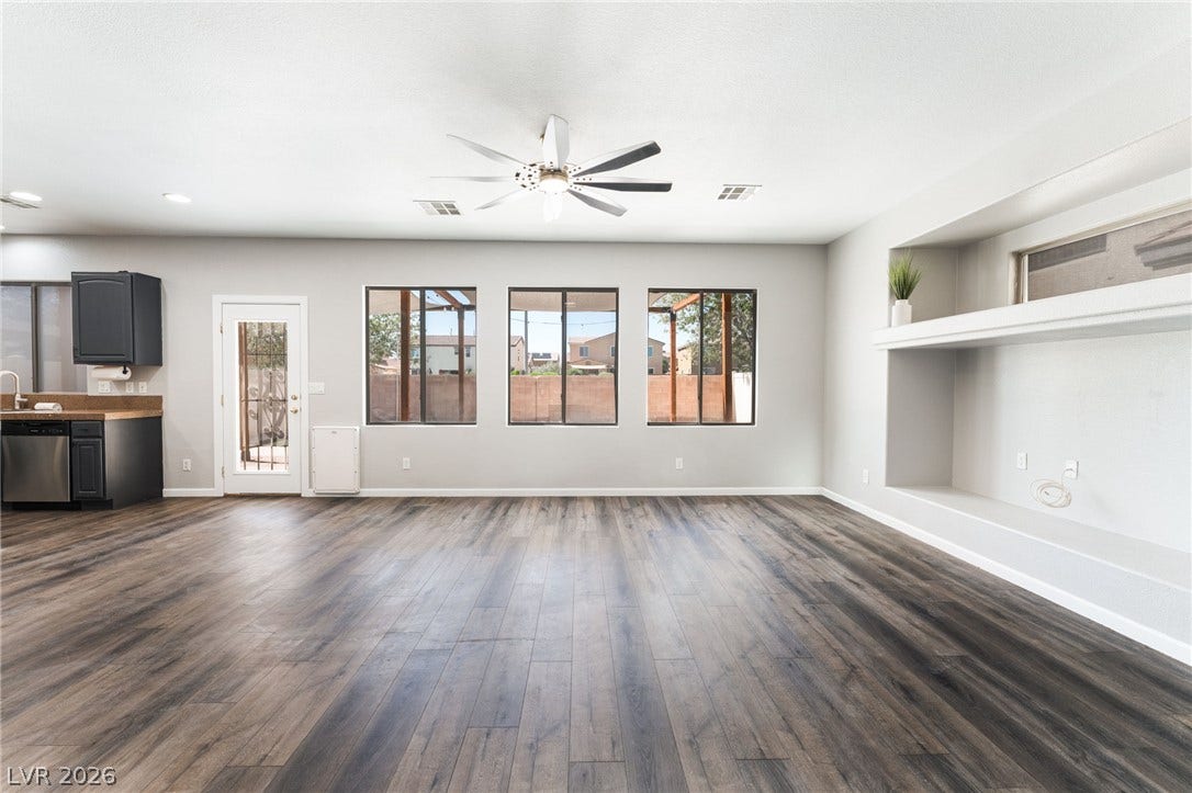 6527 Velvet Silk Street, North Las Vegas, NV 89084 Rich wood-look LVP flooring and custom built-in shelving ground this airy, open living area.