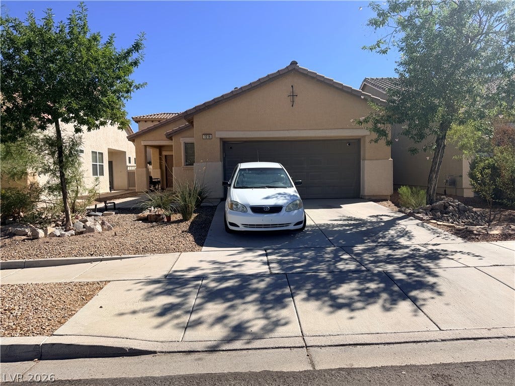 1016 Aspen Cliff Drive, Henderson, NV 89011 Warm stucco exterior and concrete driveway define this classic suburban facade under clear blue skies.