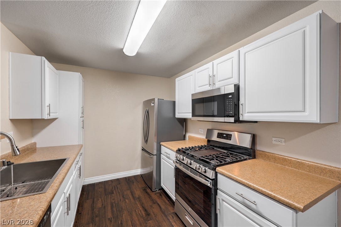 8250 N Grand Canyon Drive, #1006, Las Vegas, NV 89166 Crisp white cabinetry pairs with rich wood-look flooring in this efficiently designed kitchen.
