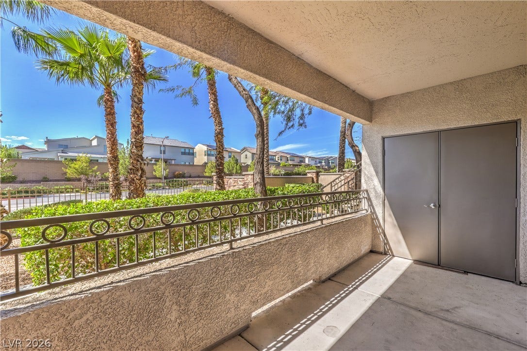 8250 N Grand Canyon Drive, #1006, Las Vegas, NV 89166 A covered patio with concrete flooring overlooks palm trees and the neighborhood beyond.