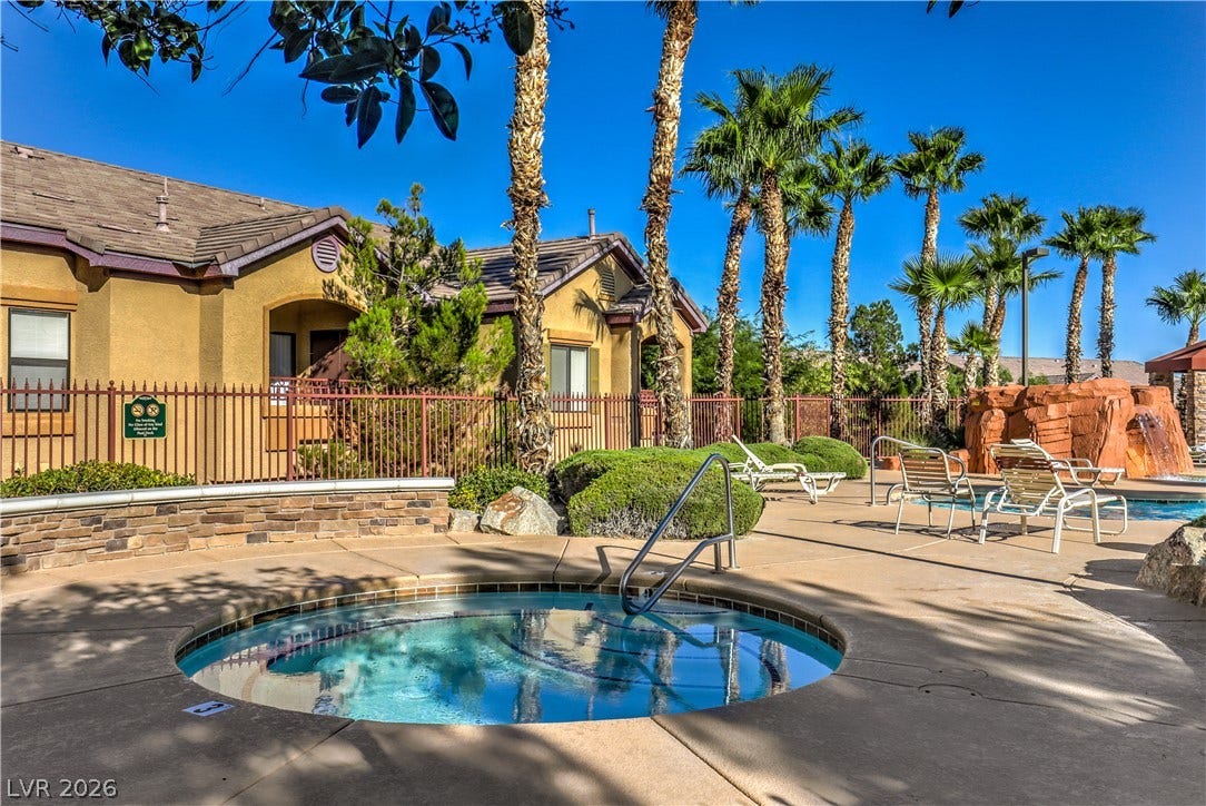 8250 N Grand Canyon Drive, #1006, Las Vegas, NV 89166 Palm trees shade a circular in-ground spa situated next to a stone-accented swimming pool.