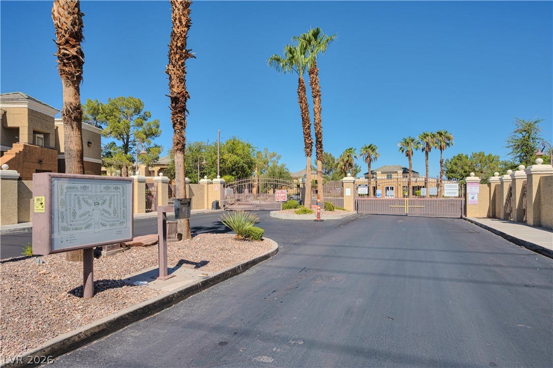 Secure gated entry welcomes residents with palm tree landscaping and paved access roads.