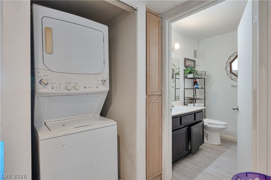 An in-unit stacked washer and dryer setup stands conveniently adjacent to the full bathroom.