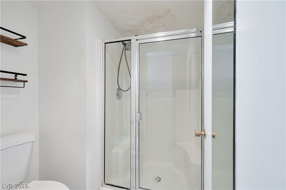 Glass doors enclose a walk-in shower with integrated seating.