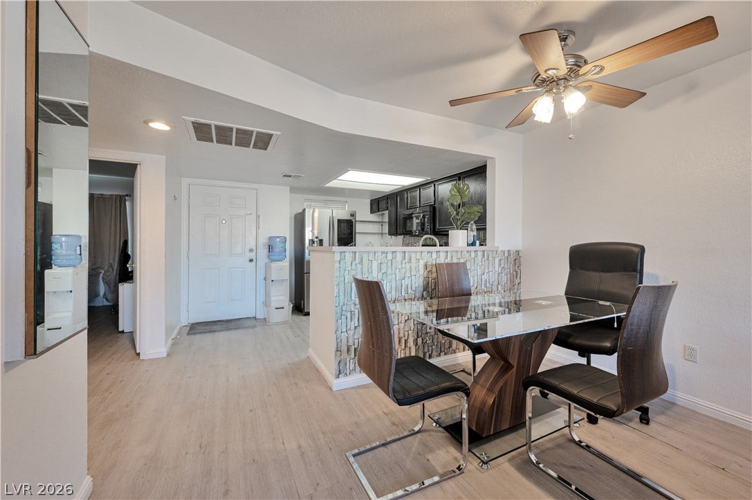 Laminate flooring runs throughout this bright dining area next to the open kitchen entry.