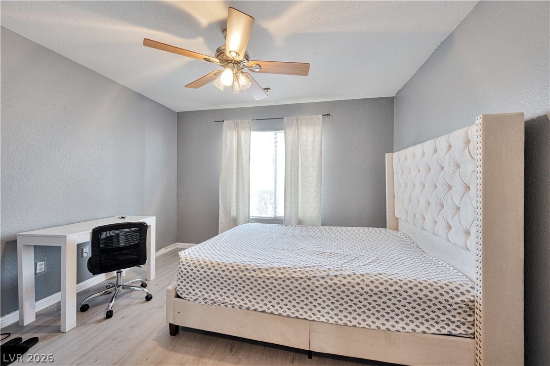 Smooth laminate flooring and a central window create a peaceful bedroom setting.