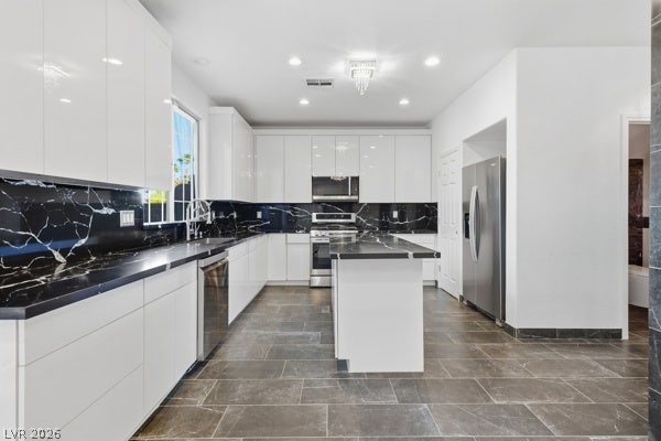 9726 Sweet Jasmine Drive, Las Vegas, NV 89148 High-gloss cabinetry, dark stone counters, and tiled flooring define this modern kitchen.