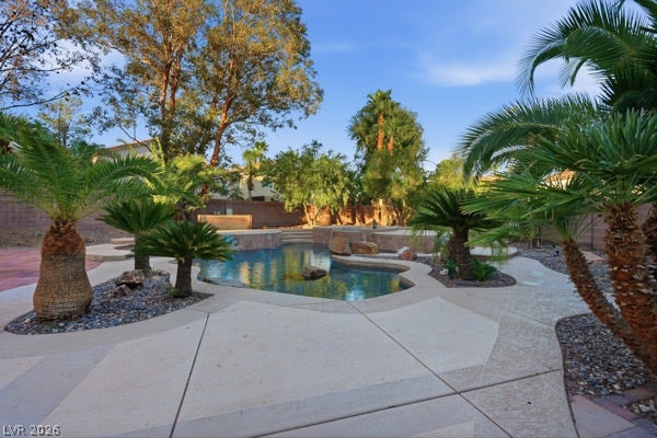 9726 Sweet Jasmine Drive, Las Vegas, NV 89148 Mature palms frame a sparkling in-ground pool surrounded by textured concrete decking.