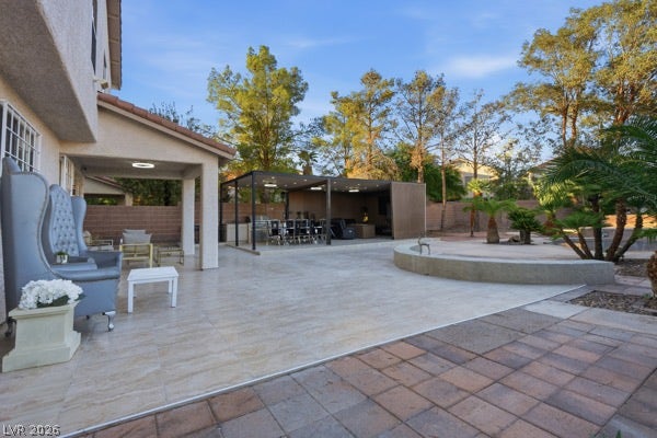 9726 Sweet Jasmine Drive, Las Vegas, NV 89148 An expansive tiled patio opens to a structured outdoor kitchen and surrounding mature trees.