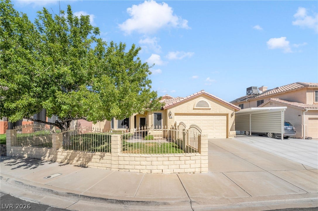 125 Heather Drive, Henderson, NV 89002 Manicured green lawn and mature shade trees frame this classic stucco home with gated fencing.