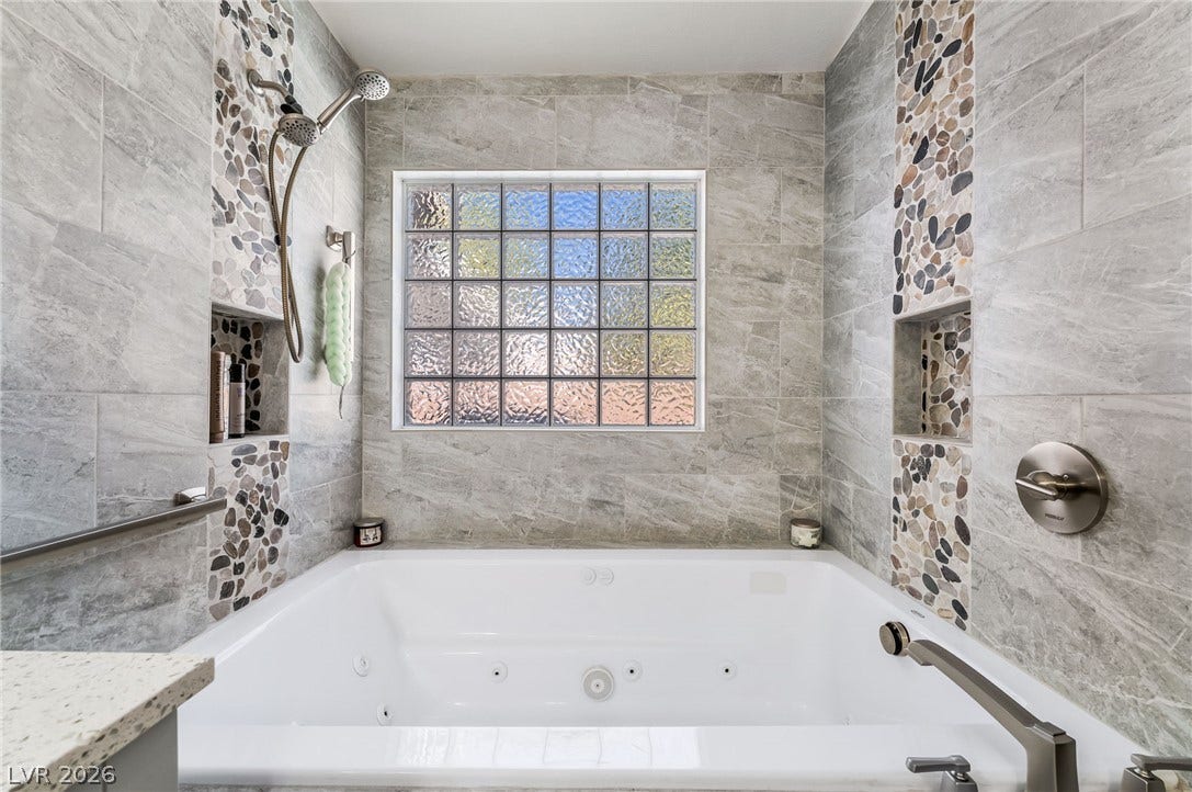125 Heather Drive, Henderson, NV 89002 Fine tilework surrounds a deep soaking tub positioned beneath a textured glass window.