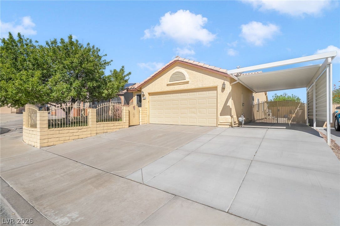 125 Heather Drive, Henderson, NV 89002 An expansive concrete driveway leads past a gated carport to the attached garage.
