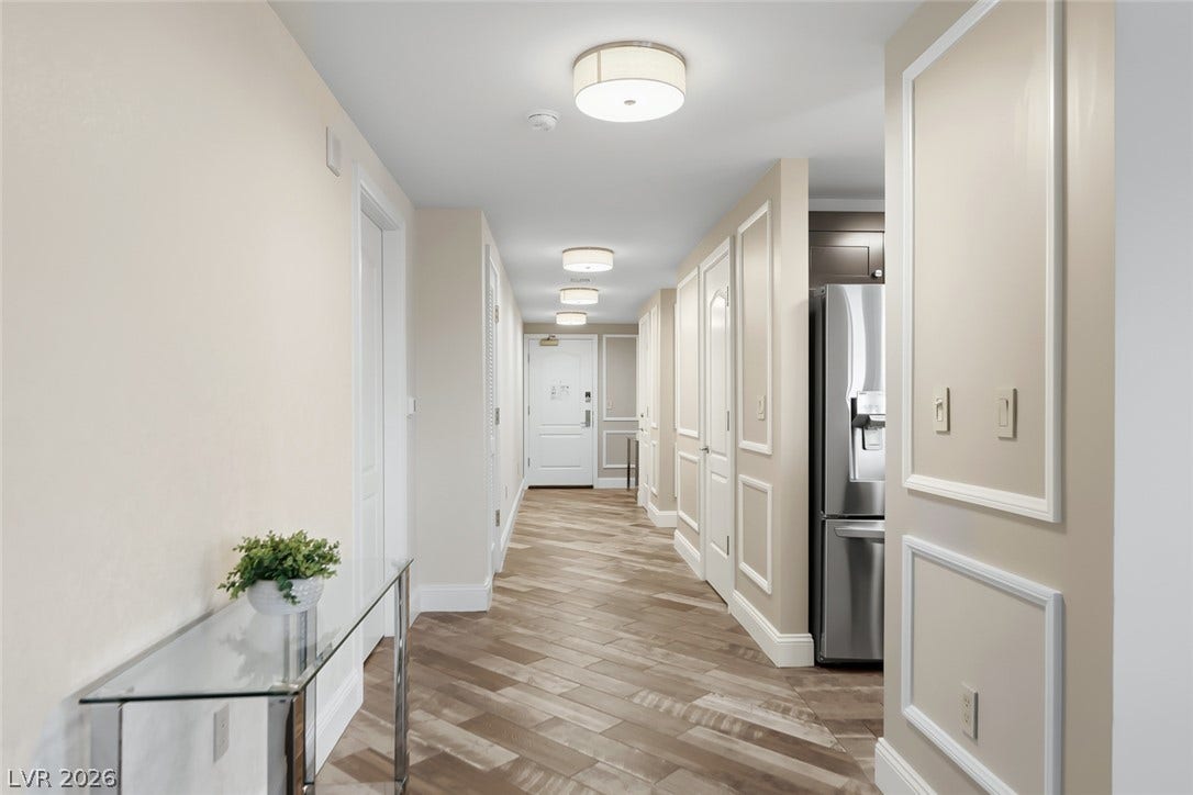30 Strada Di Villaggio, #151, Henderson, NV 89011 Crown molding and elegant wall paneling frame a long hallway paved in wood-look tile flooring.