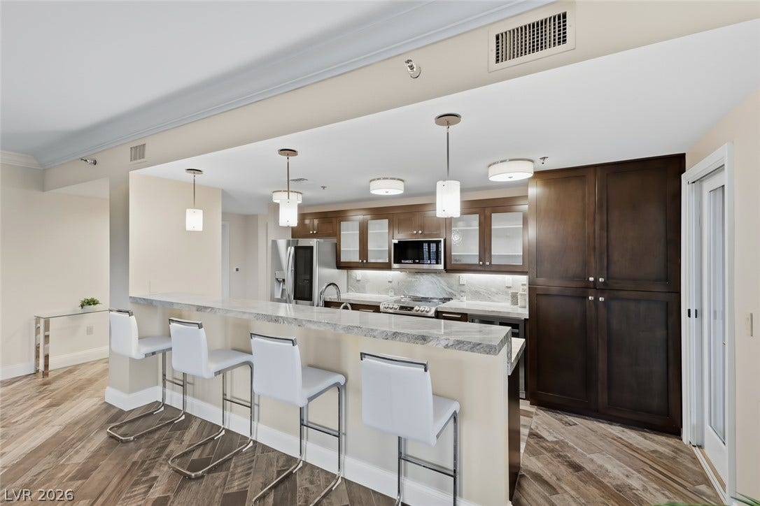 30 Strada Di Villaggio, #151, Henderson, NV 89011 Rich wood cabinetry contrasts beautifully with granite countertops in this open kitchen layout.