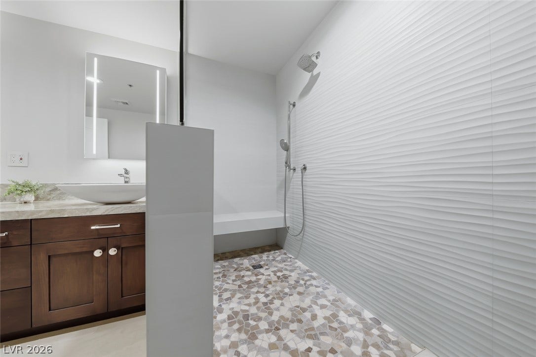 30 Strada Di Villaggio, #151, Henderson, NV 89011 Textured wall tiles and pebble flooring create a spa-like atmosphere in this modern shower.