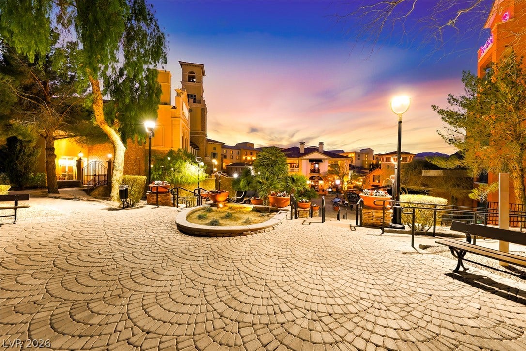 30 Strada Di Villaggio, #151, Henderson, NV 89011 Elegant stone pavers wind through beautifully manicured common areas beneath an illuminated evening sky.