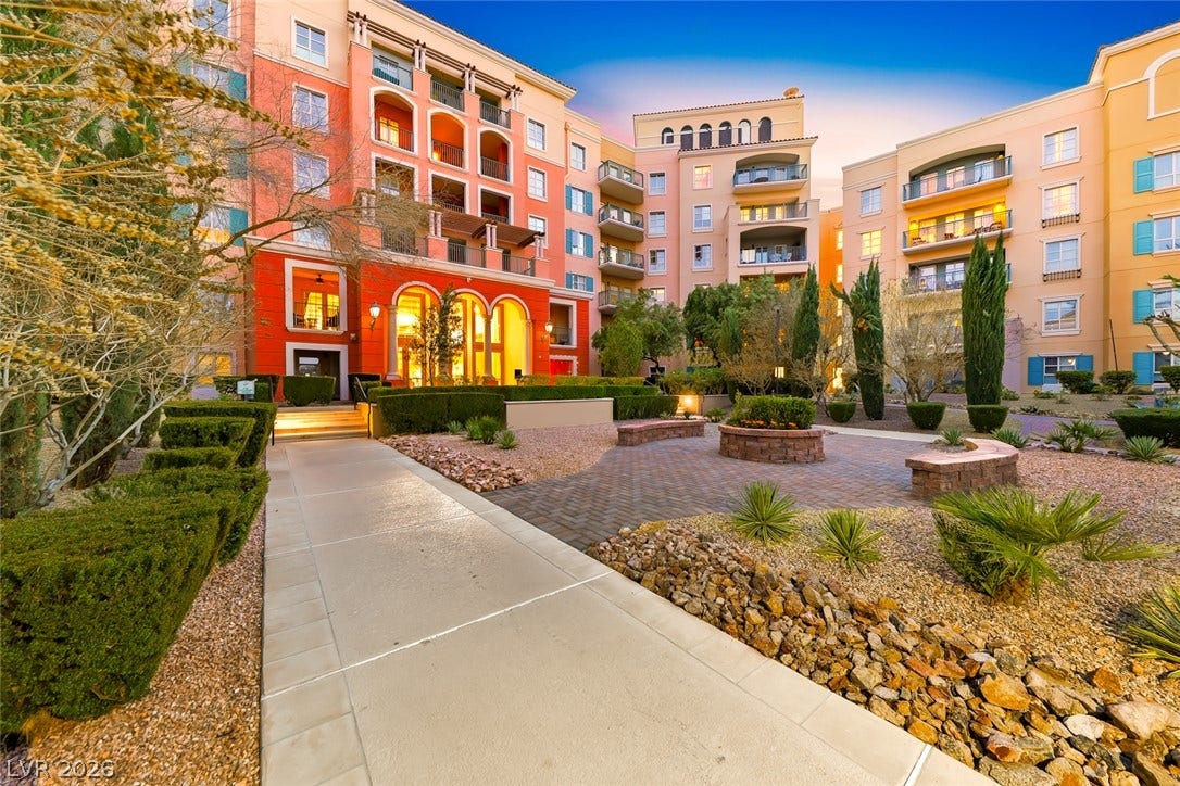 30 Strada Di Villaggio, #151, Henderson, NV 89011 Mediterranean-inspired multi-story residential buildings surround a landscaped courtyard with paved walkways and manicured hedges.