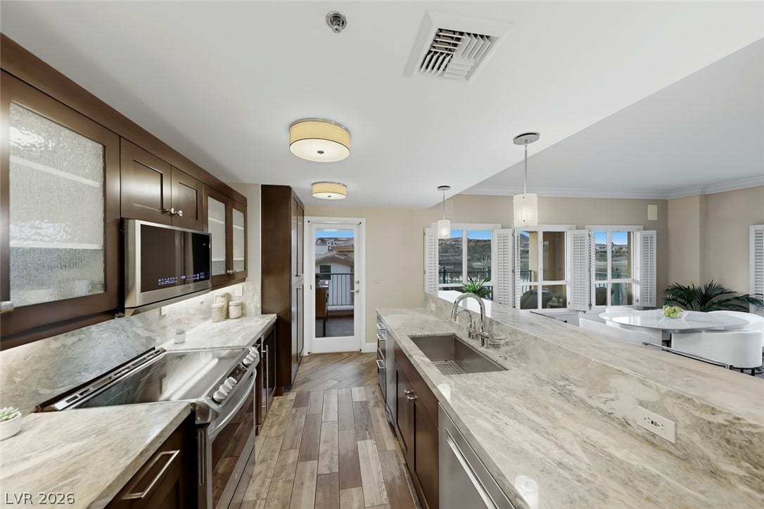30 Strada Di Villaggio, #151, Henderson, NV 89011 Rich wood cabinetry contrasts beautifully with swirling stone countertops in this modern workspace.