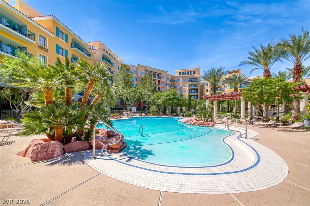 30 Strada Di Villaggio, #151, Henderson, NV 89011 Lush palm trees surround a sparkling blue swimming pool within the landscaped courtyard.