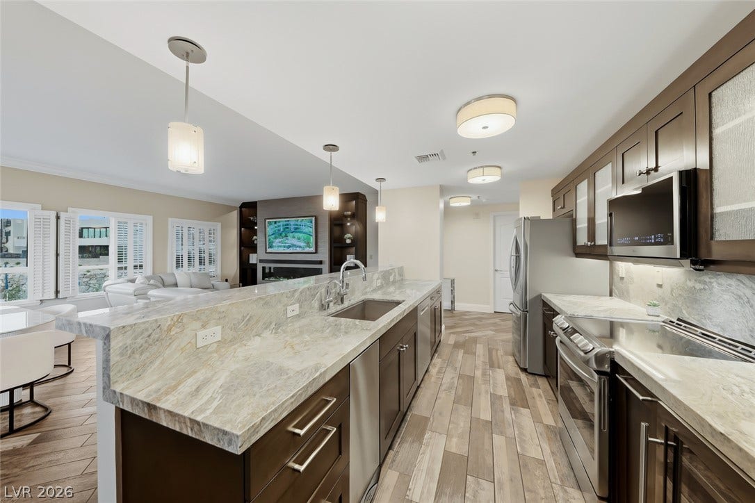 30 Strada Di Villaggio, #151, Henderson, NV 89011 Polished stone countertops and seamless flooring define this modern open-concept kitchen.