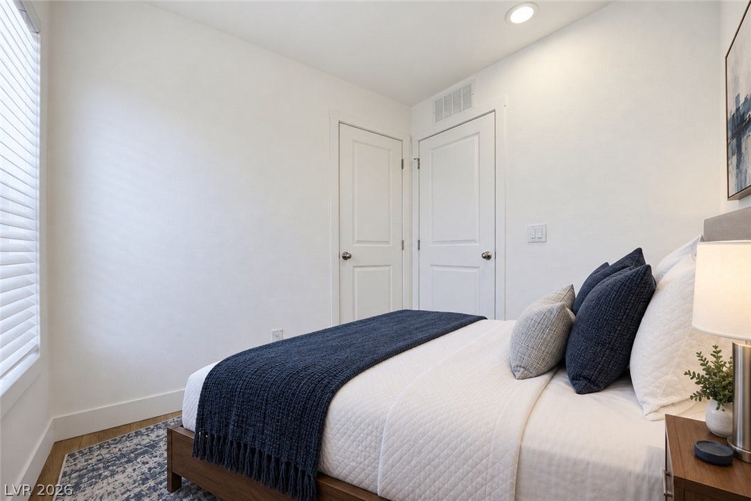 Recessed lighting and warm wood flooring enhance this serene bedroom space.