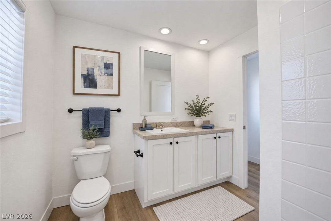Gleaming hardwood floors and a modern stone-counter vanity anchor this immaculate bathroom space.